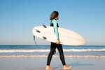 海边女子持冲浪板漫步