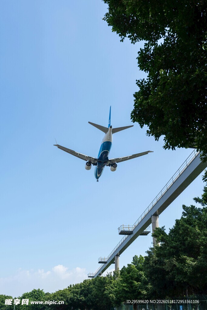 飞机低空飞过绿树与桥梁