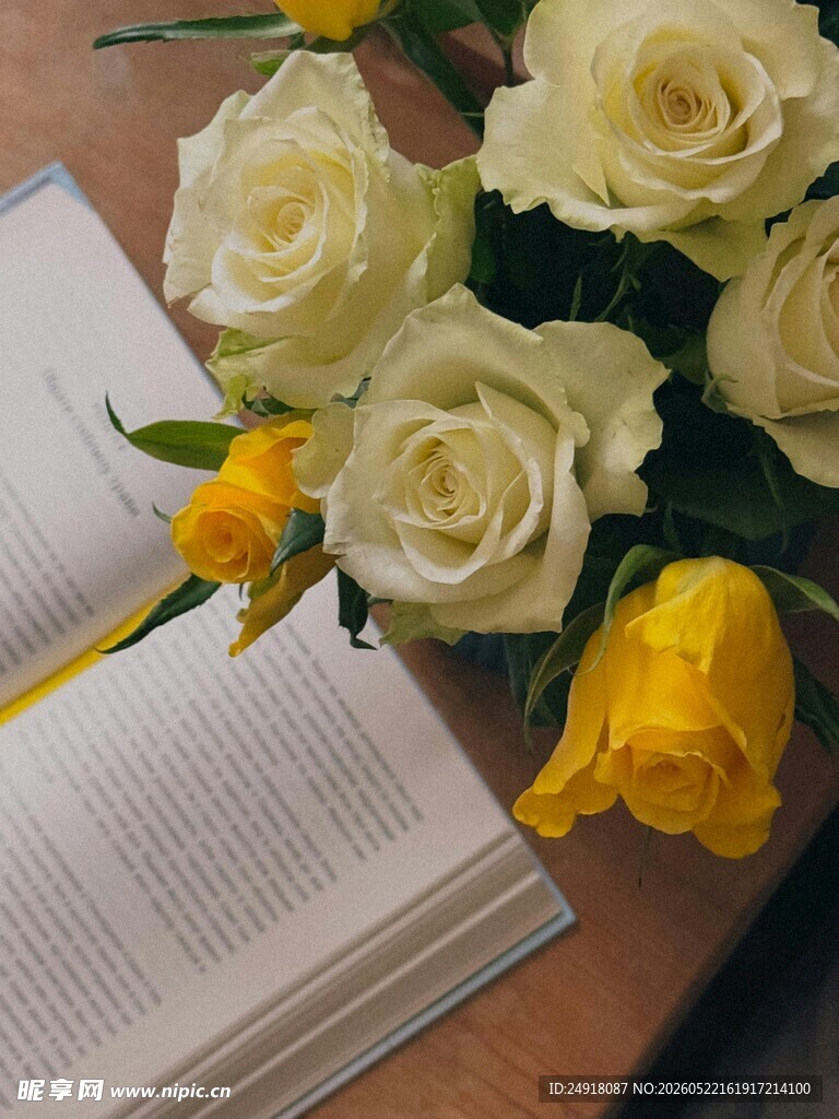 书本旁的优雅白黄玫瑰花束