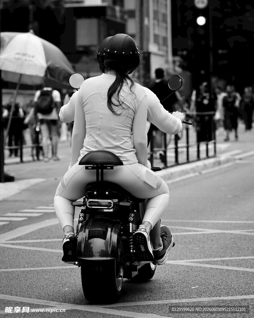 女子骑摩托穿行于城市街道