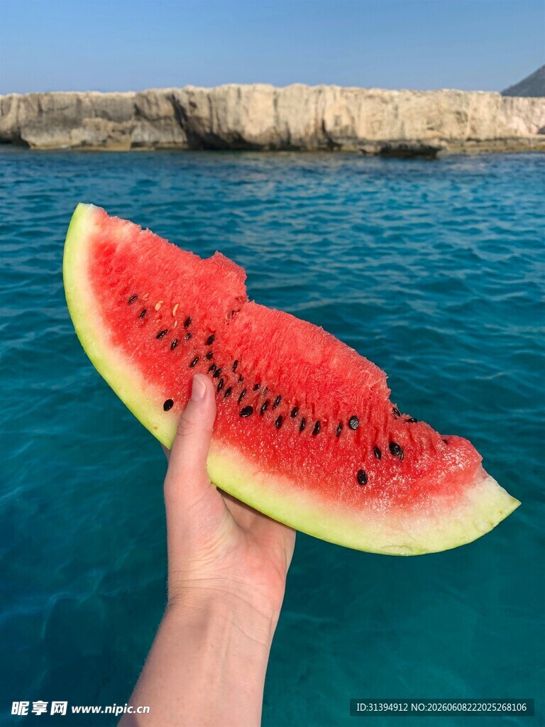 海边手拿西瓜的惬意瞬间