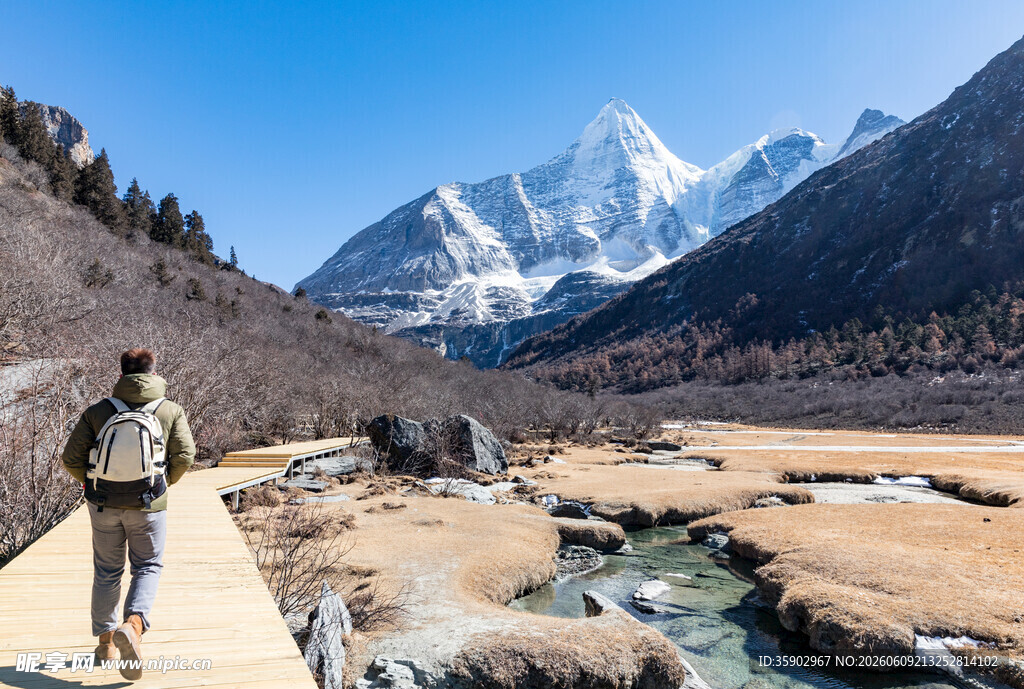 徒步者穿行于雪山河畔