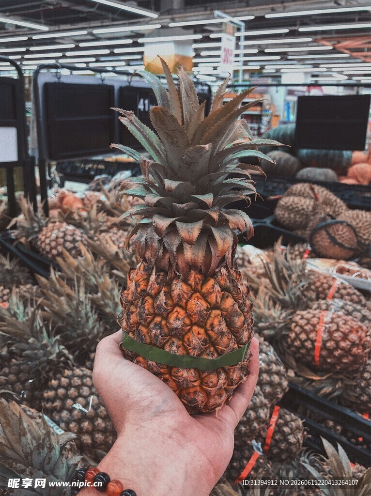 手捧新鲜菠萝于水果摊