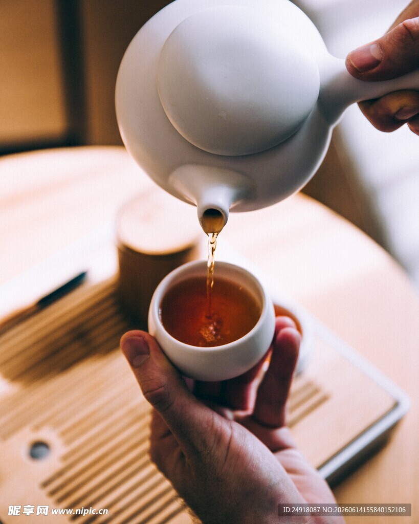 手捧杯盏接茶壶倾茶