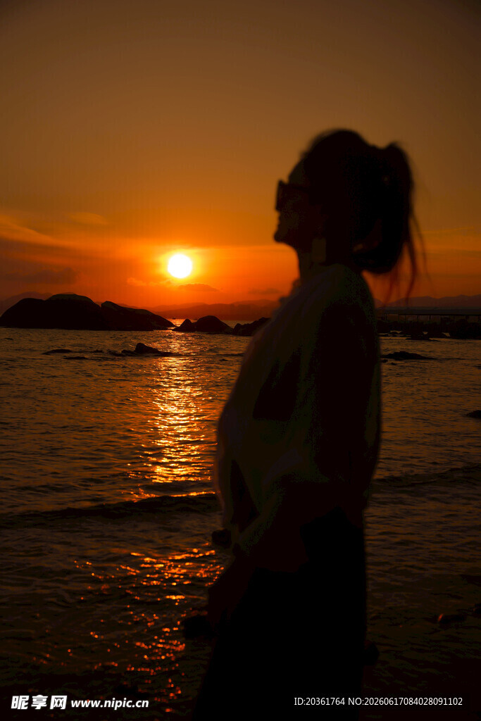 夕阳下海边沉思的女子