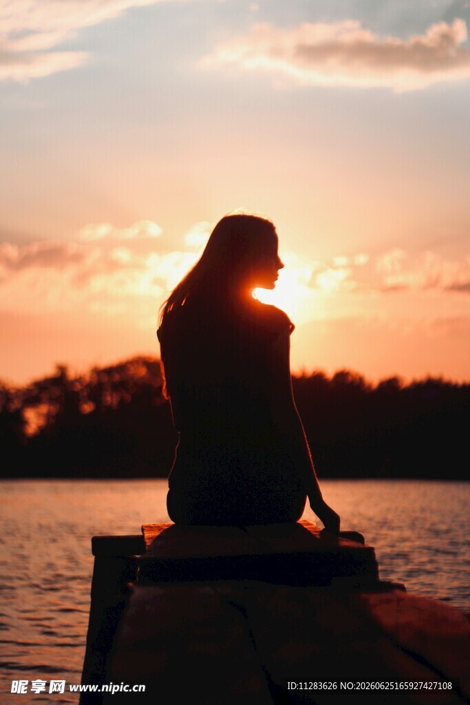 夕阳下独坐水边的女子