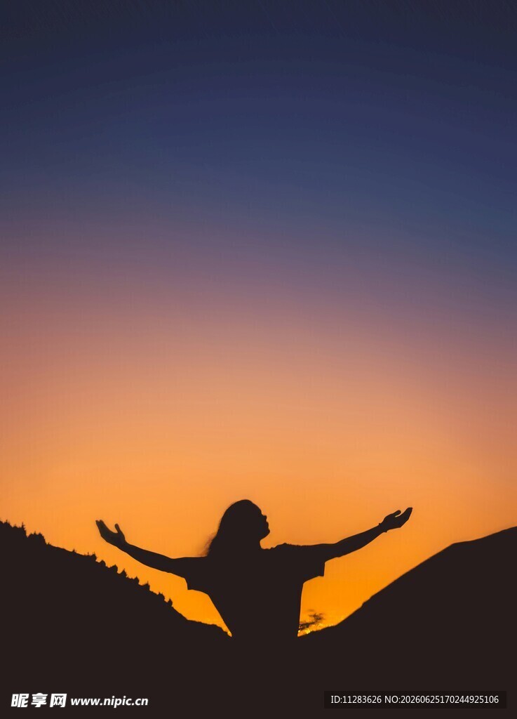 夕阳下张开双臂的人的剪影