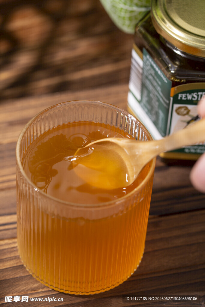 木勺舀蜂蜜于玻璃杯