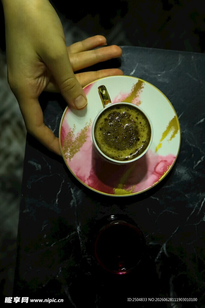 手托精美花纹杯碟中的咖啡