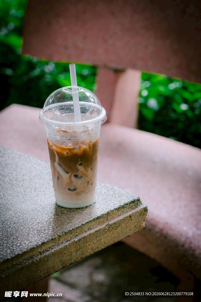 户外木桌上的透明塑料杯咖啡