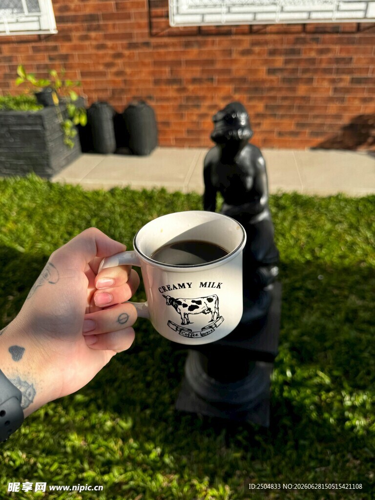 手持咖啡杯与雕像的场景