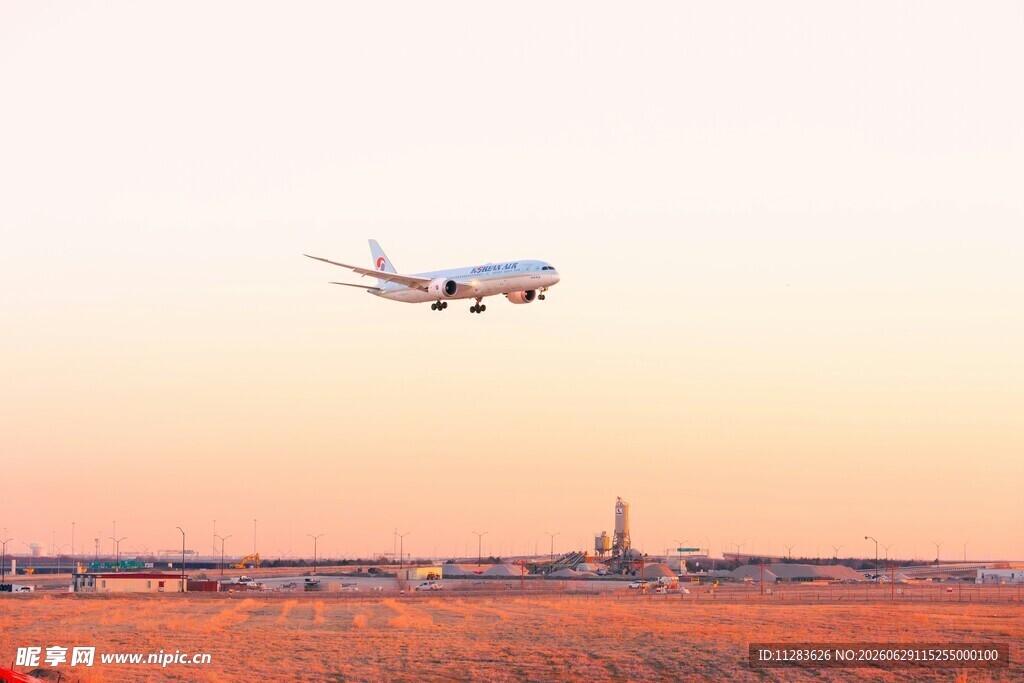 夕阳下飞机低空飞过机场