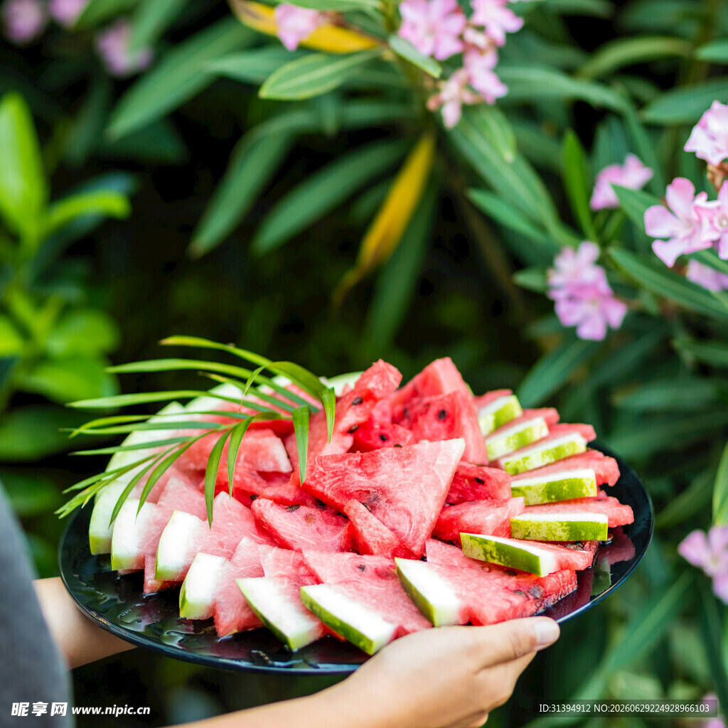 手捧西瓜盘于绿植花丛间