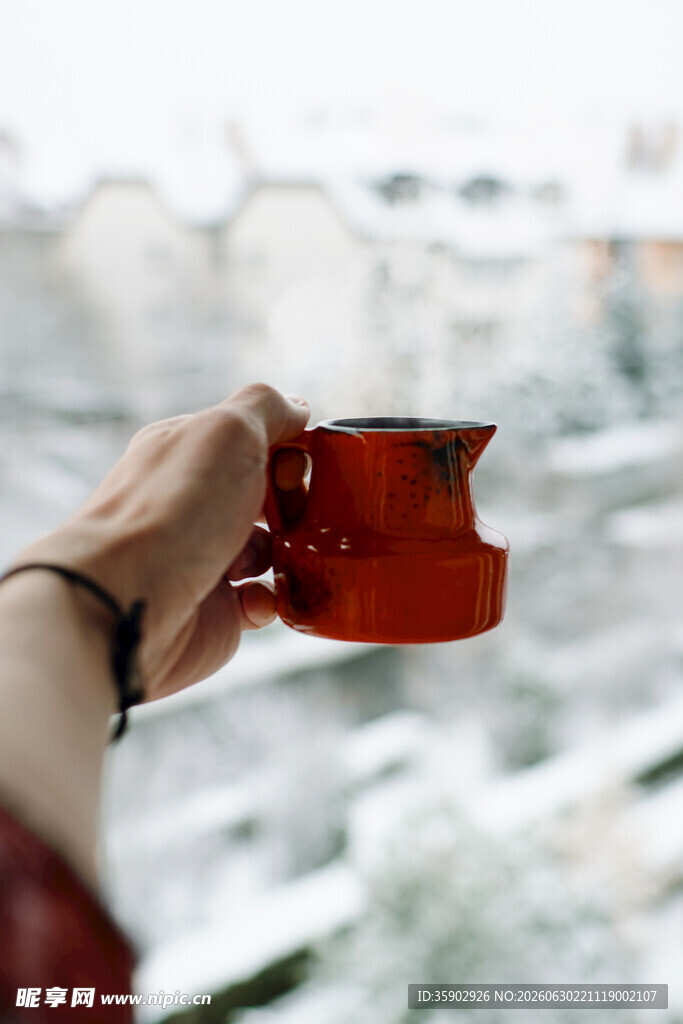 手持红杯赏窗外雪景
