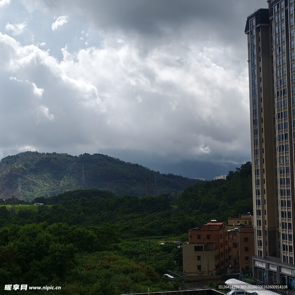高楼旁的山峦与多云天空