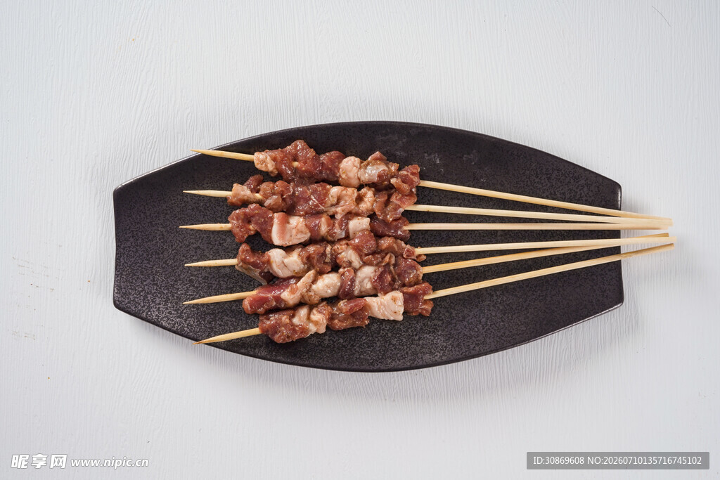 美味烤肉串摆于黑色盘上