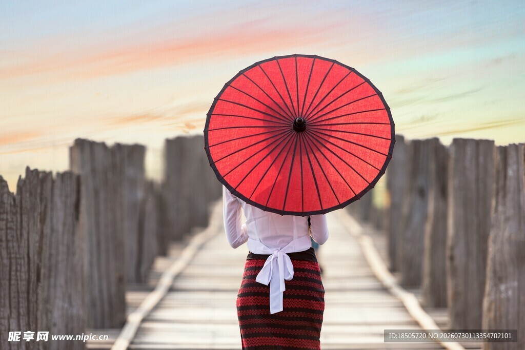 撑红伞女子漫步木栈道