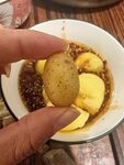 手拿土豆块配碗中食物