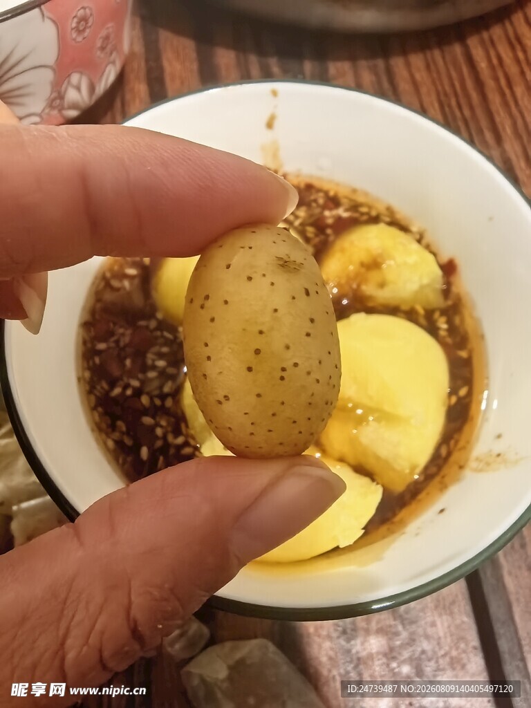 手拿土豆块配碗中食物