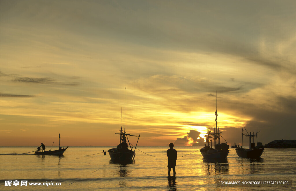 夕阳下的海边船只与人影
