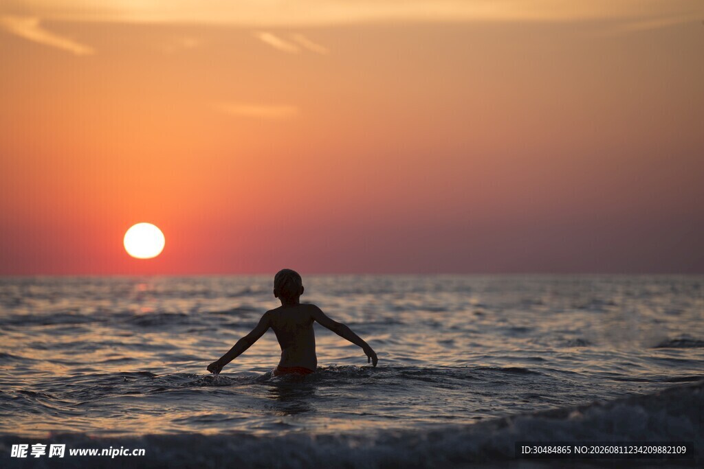 夕阳下海中漫步的身影