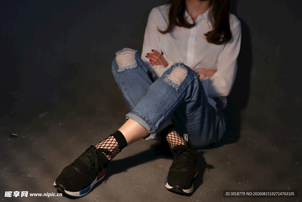 时尚女孩坐地展示破洞牛仔裤