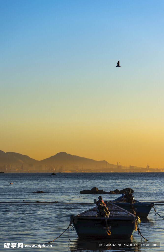 海边日落时的渔船与飞鸟