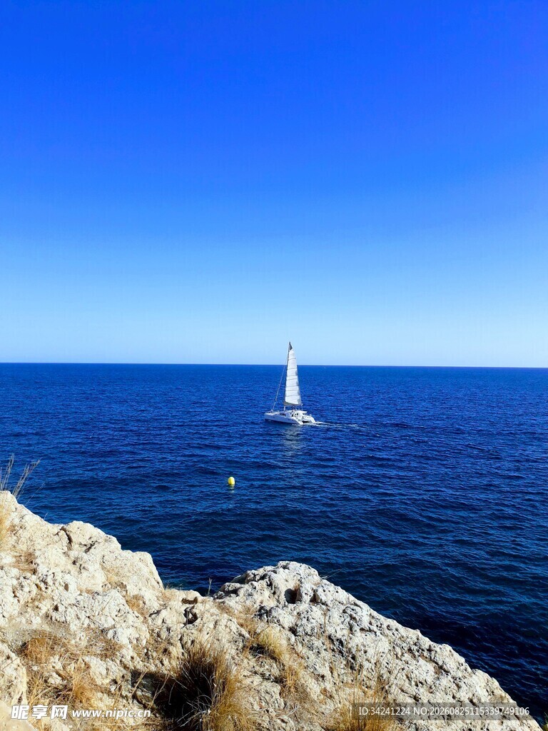 海边礁石旁的白色帆船