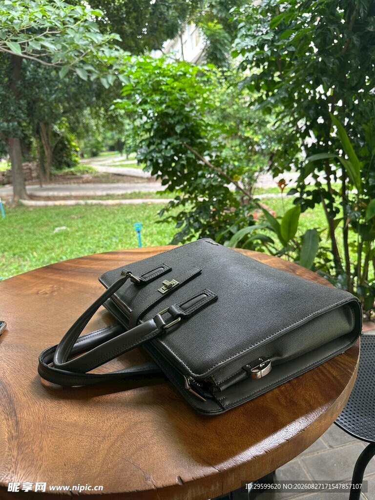 户外木桌上的黑色精致手提包