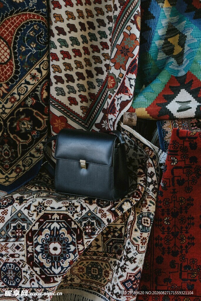 多彩织物旁的精致黑色皮包