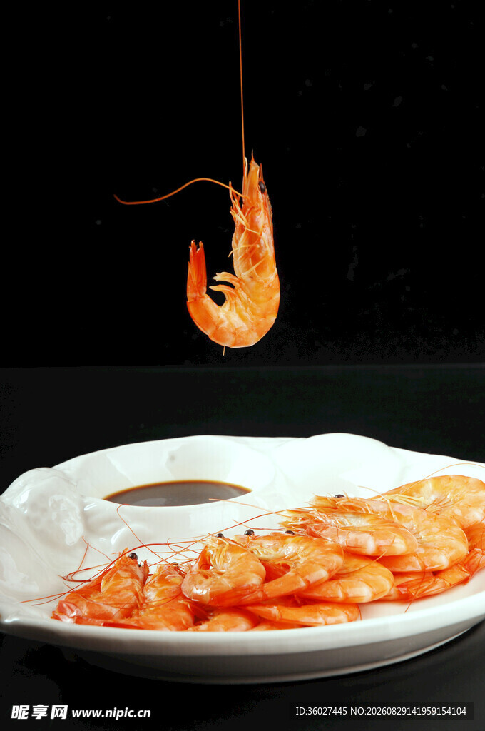 鲜虾悬垂于蘸料盘上方