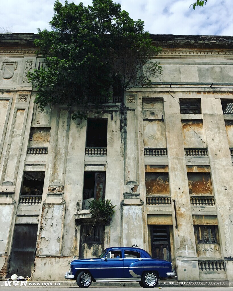 废弃建筑前的复古蓝色汽车