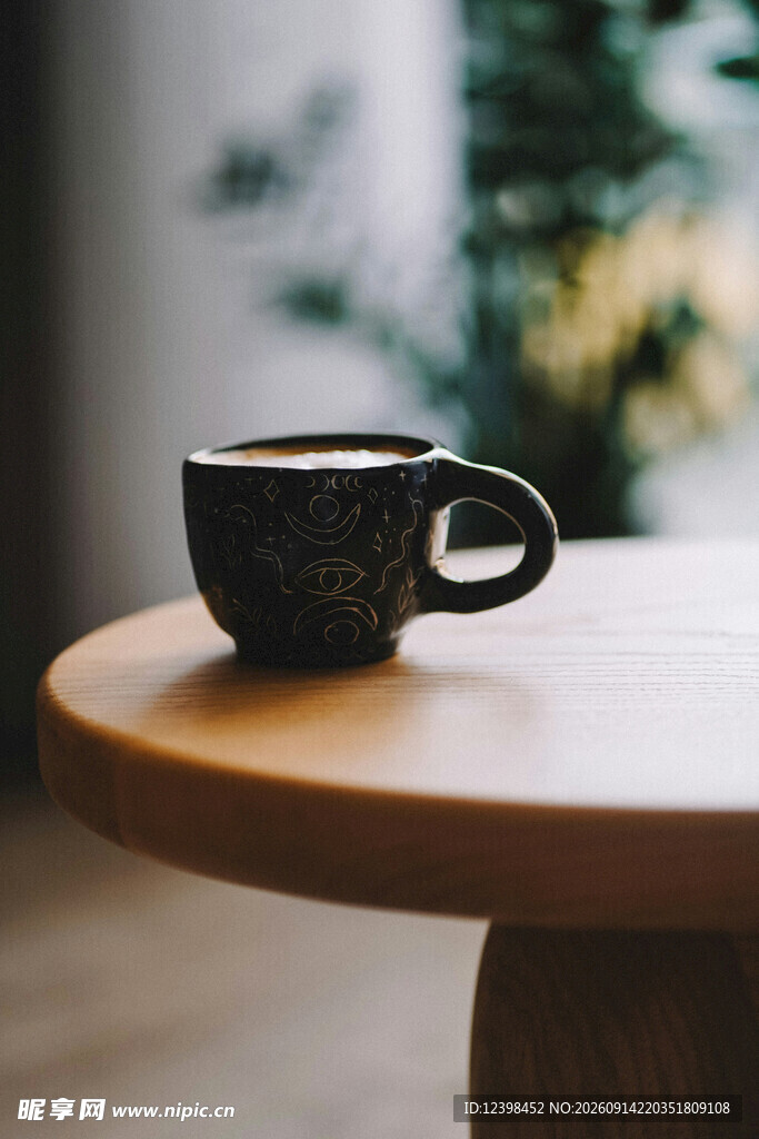 木桌上的黑色咖啡杯