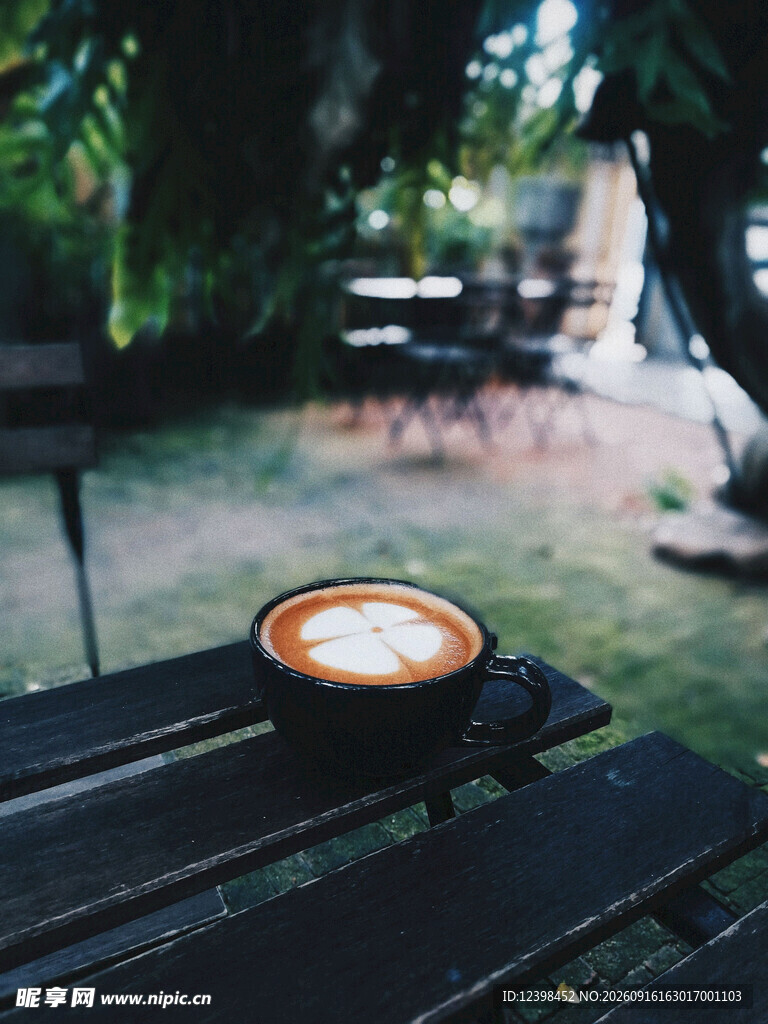 户外木桌上的一杯拉花咖啡