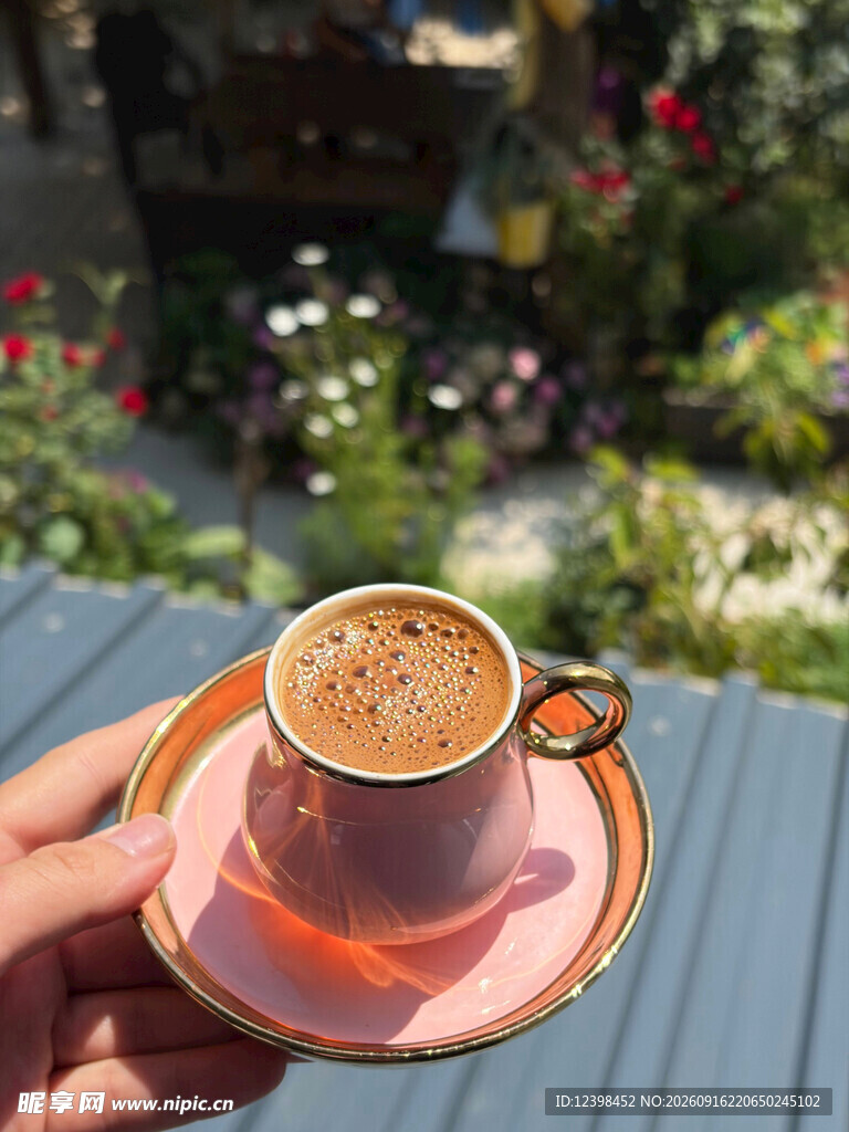 手捧精致咖啡杯赏户外景致