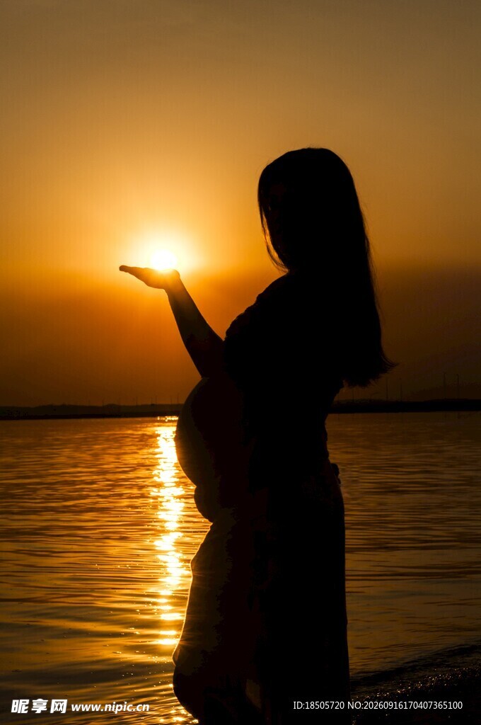 夕阳下的孕妇海边温柔剪影