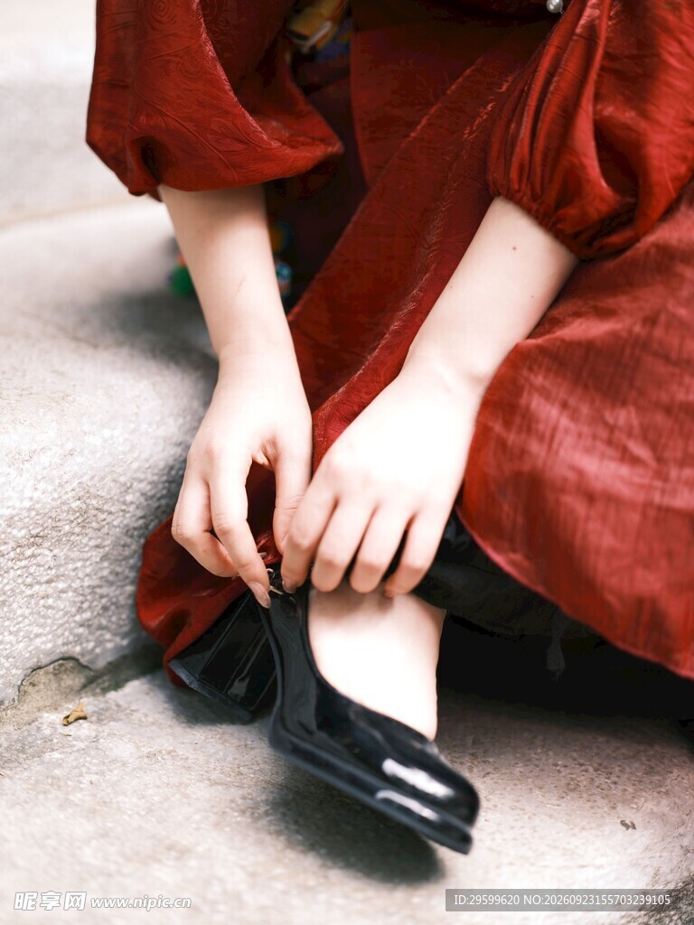 红衣女子蹲身系鞋带