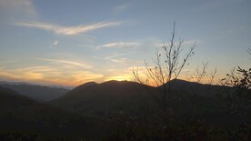 夕阳下蓝天白云染色山顶枯草