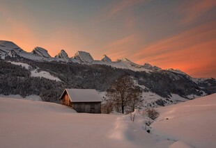 雪后山间小屋的绚丽黄昏