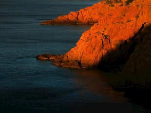 夕阳下的海边红色崖壁