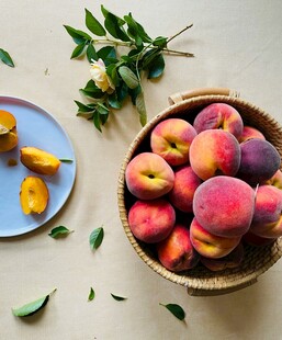 新鲜桃子摆放在篮中与盘边