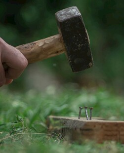 手挥木槌钉钉子于草地