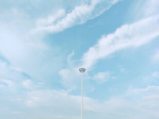 蓝天白云下的高耸路灯