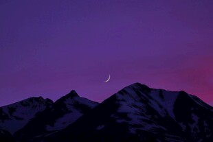 紫色夜幕下的雪山与新月