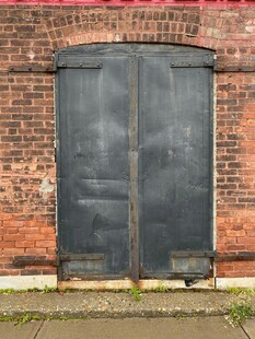 老旧砖墙前的双扇铁门