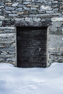 雪覆石墙中的古朴木门