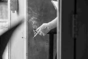 窗边手持香烟的手部特写