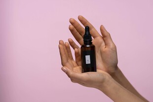 双手捧持的深色小瓶精油