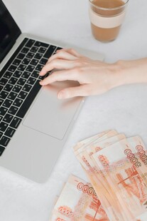 手在电脑旁与现金相伴