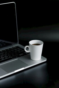 笔记本电脑旁的白色咖啡杯